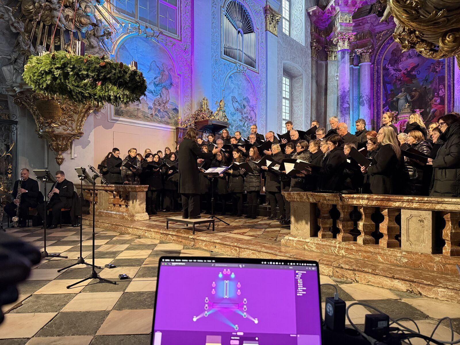 Barocke Kirche in blau-violettes Ambientelicht getaucht – Chor und Orchester beim Konzert, im Vordergrund das Lichtpult