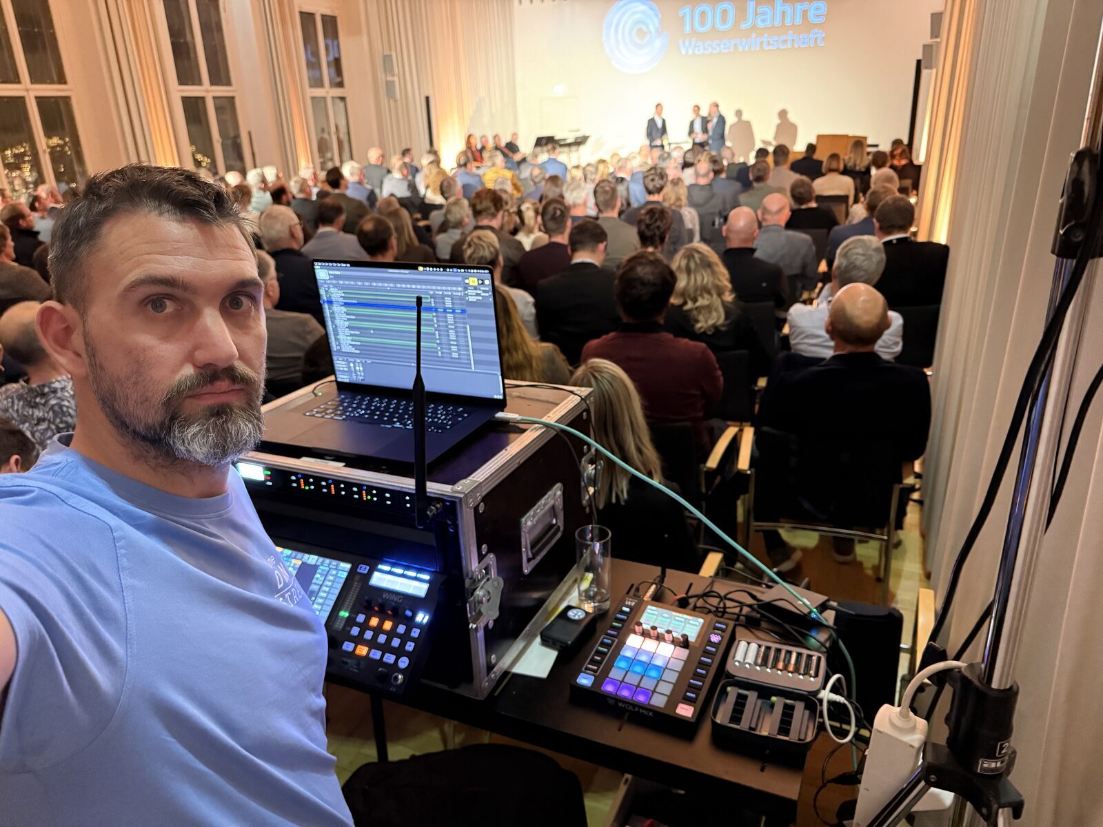 Zuspiel-Setup am FOH-Platz: Laptop mit Zeitleiste, Wing-Pult und Wolfmix, im Hintergrund das Publikum vor der Bühne