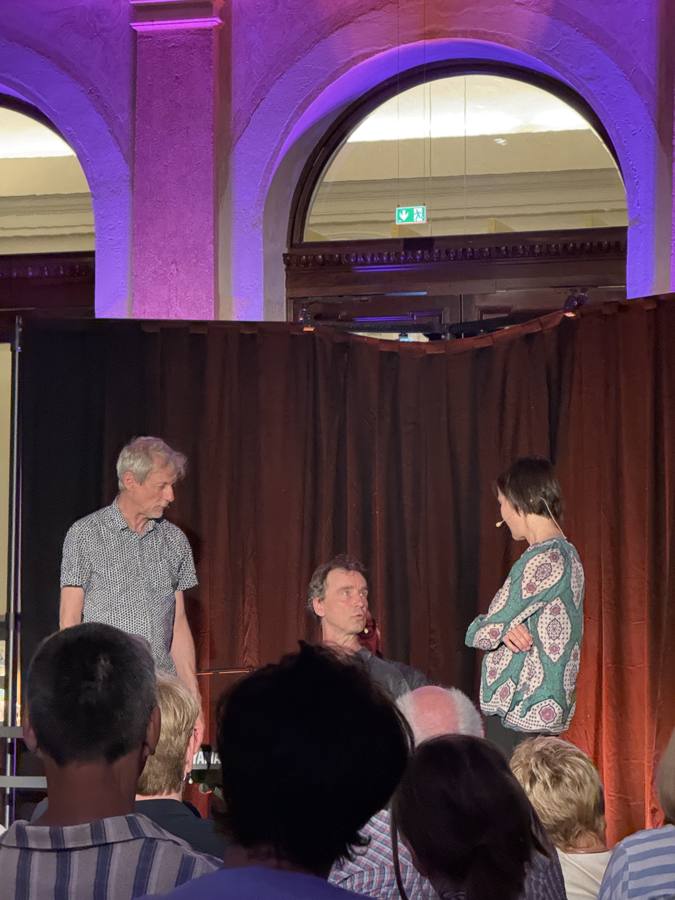 Foyer-Atmosphäre nach der Show, lila Beleuchtung, Publikum im Gespräch