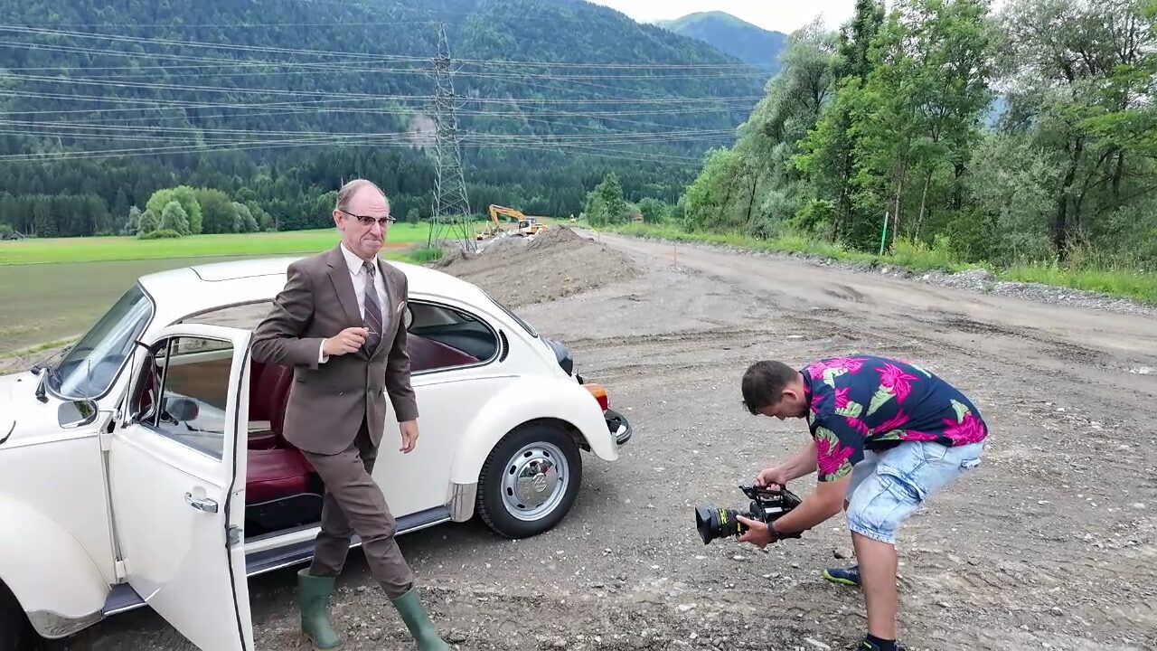 Helfried steigt aus dem VW Käfer, Kamera dokumentiert